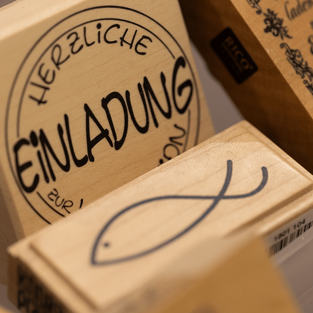 Holzstempel mit dem Schriftzug Herzliche Einladung